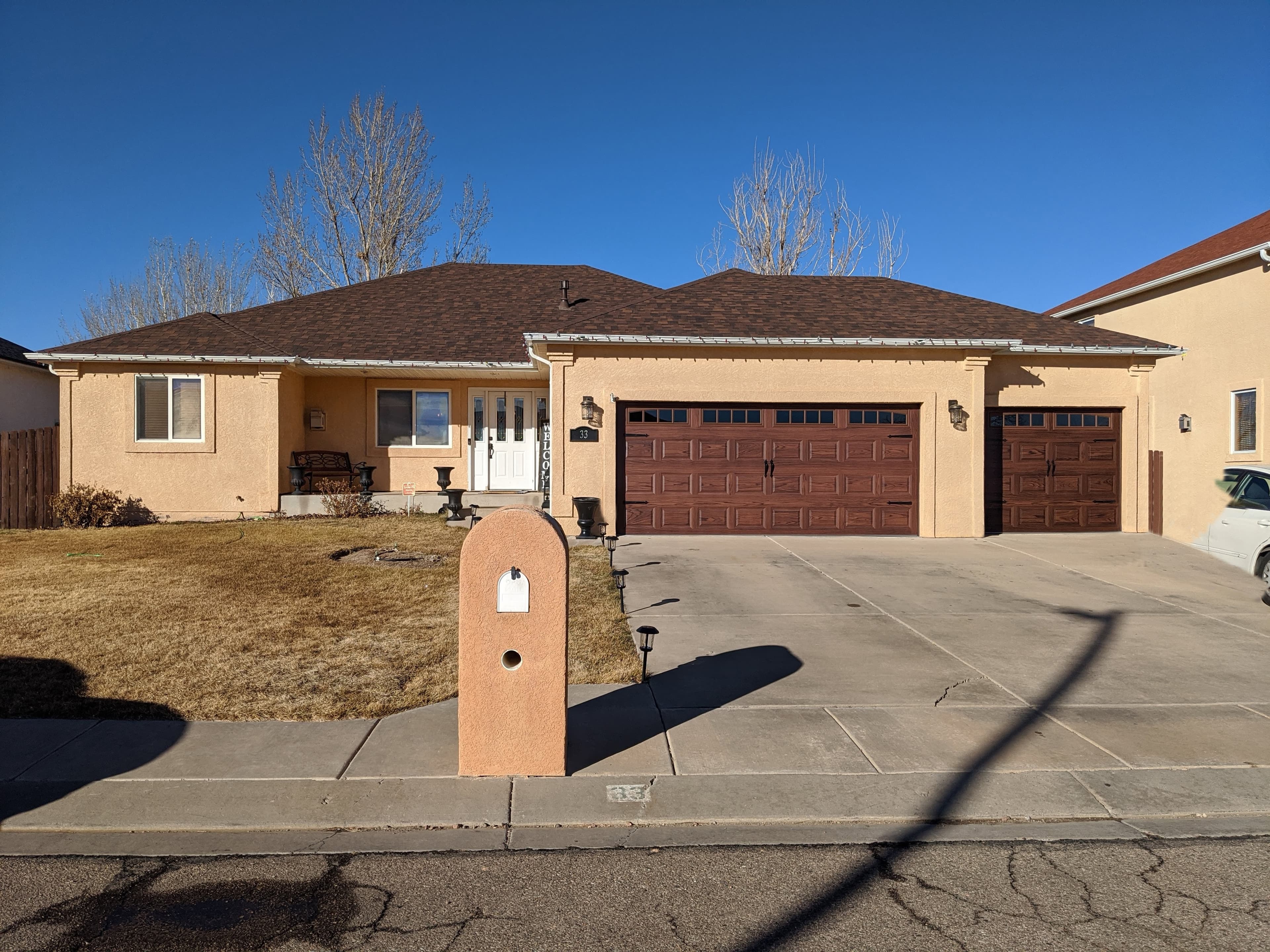 Matching wood-look carriage garage doors installed on a stucco ranch home in Pueblo